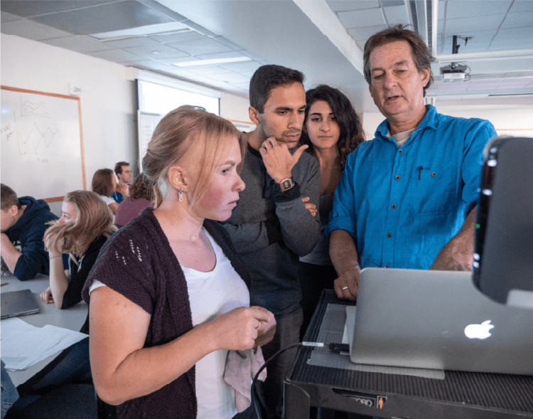 Katie Ryan in a group of people all looking at a laptop