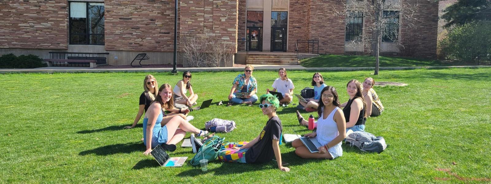 A group of mentors sitting outside on a field