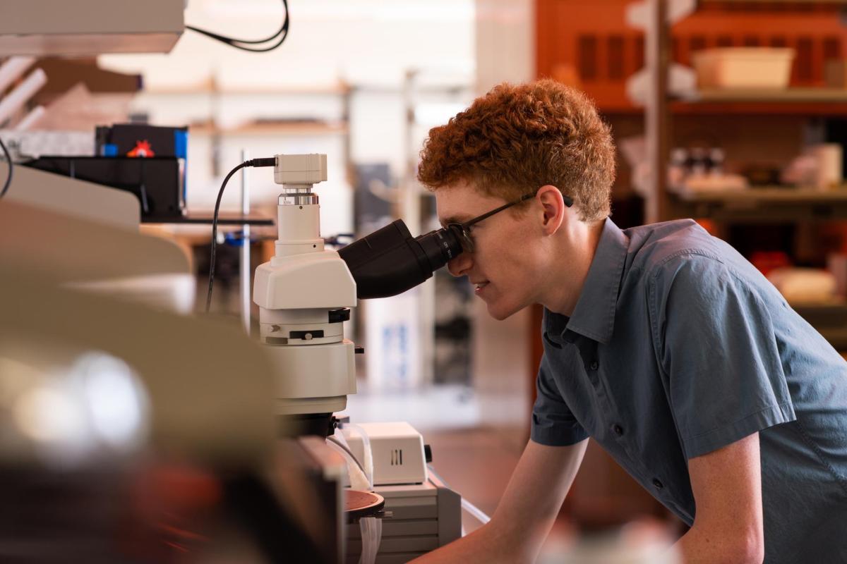 Student looking through a microscope.