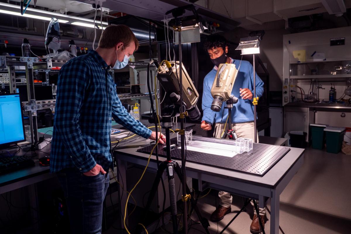 Kaushik Jayaram and a student working at a table in his lab.