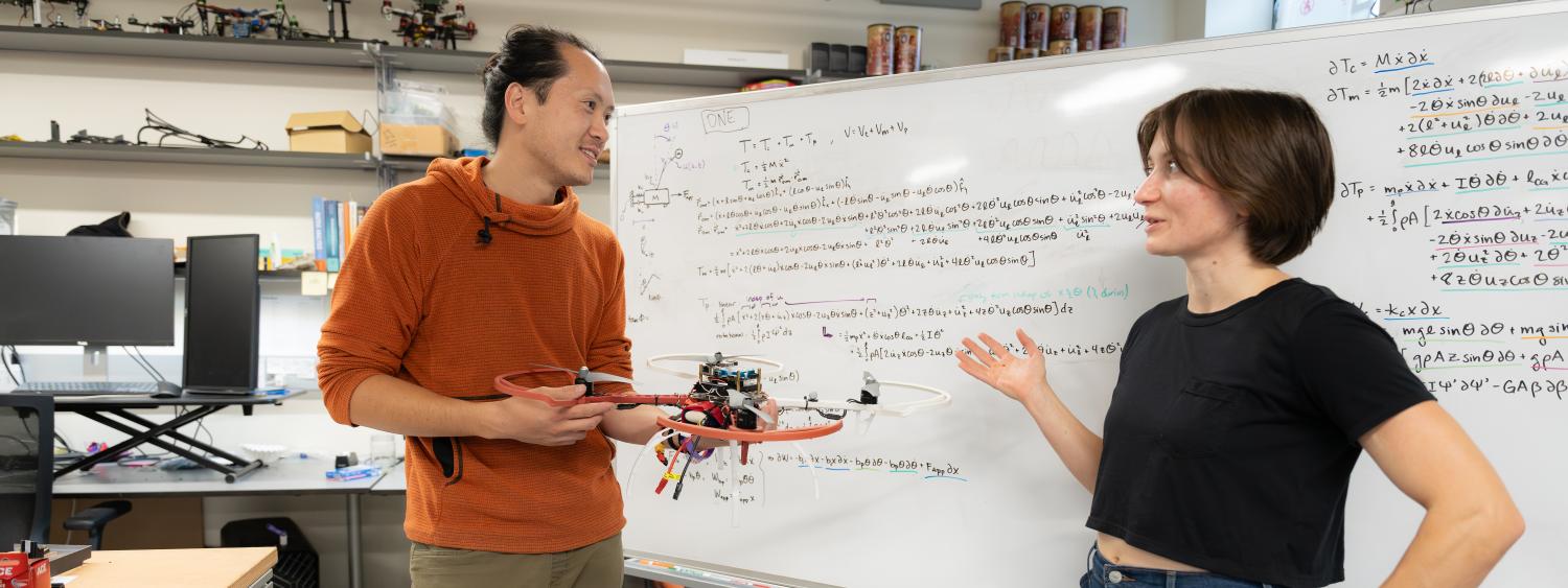 Zoe Turin and Eugene Rush in front of a white board with a small UAS.