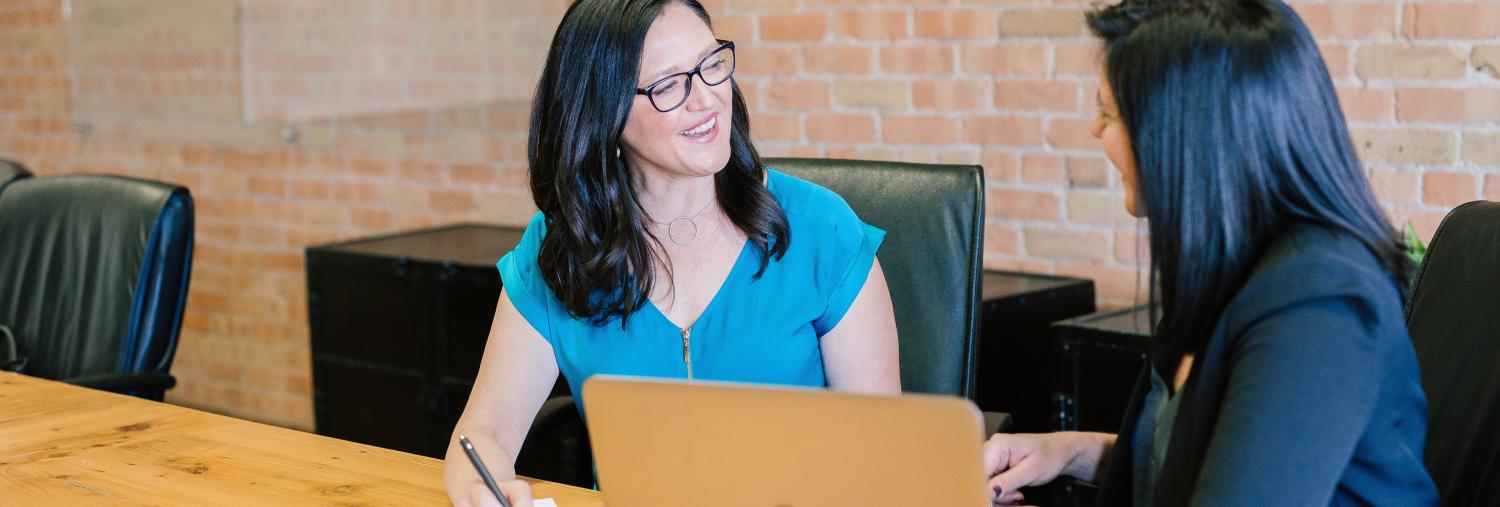 Two women meeting and consulting with a laptop and notebook