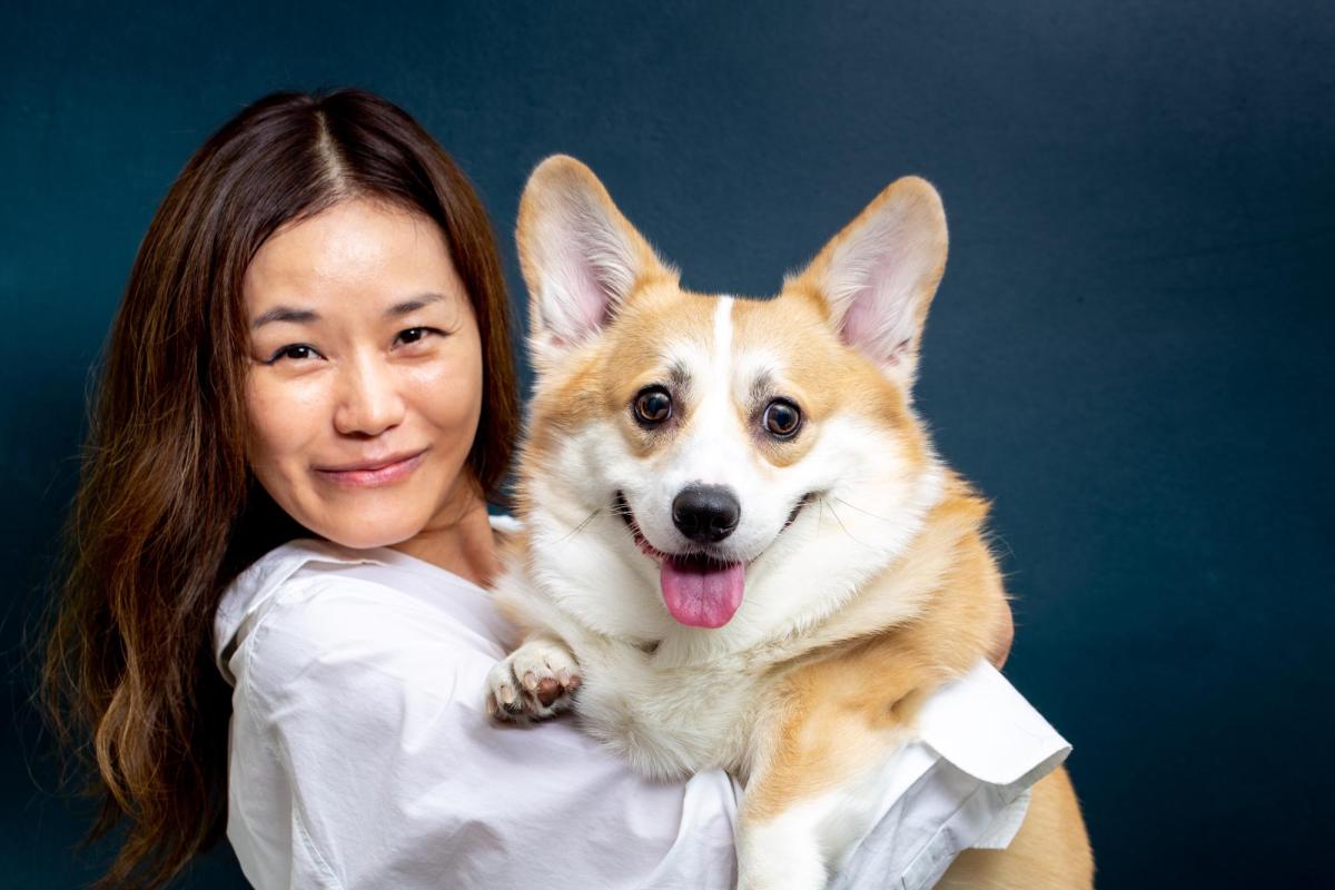 A veterinarian holds a dog, both of whom appear to smile at the camera.