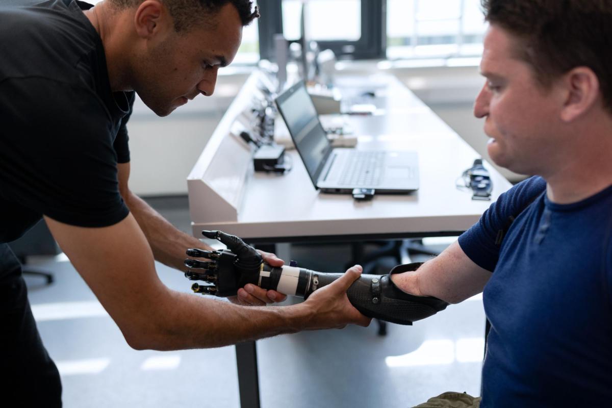 A physical therapist helps a man adjust his prosthetic.