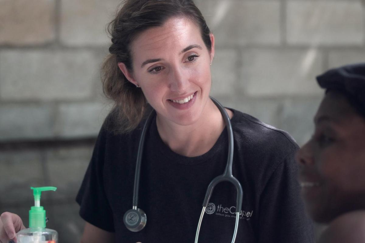 A nurse helps a person and appears to be listening to them speaking.