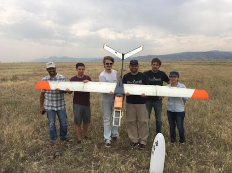 Students standing with an airplane drone in open field