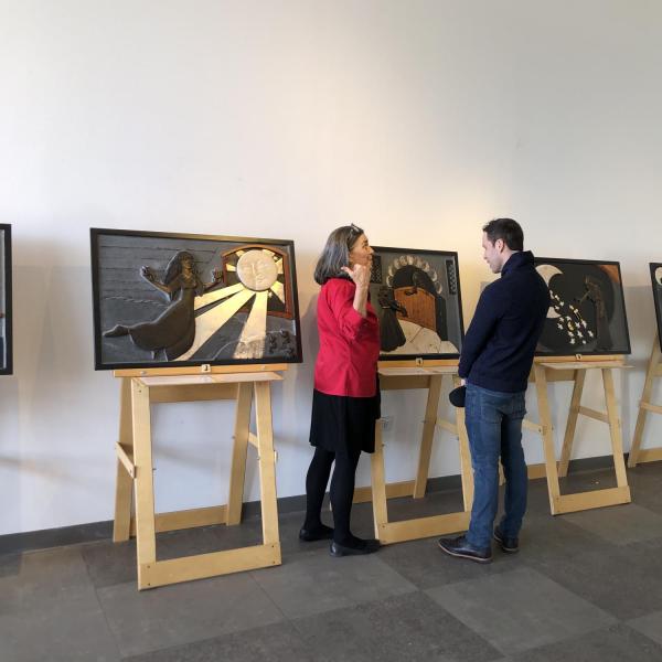 Artist Ann Cunningham with visitor in front of her story panels.