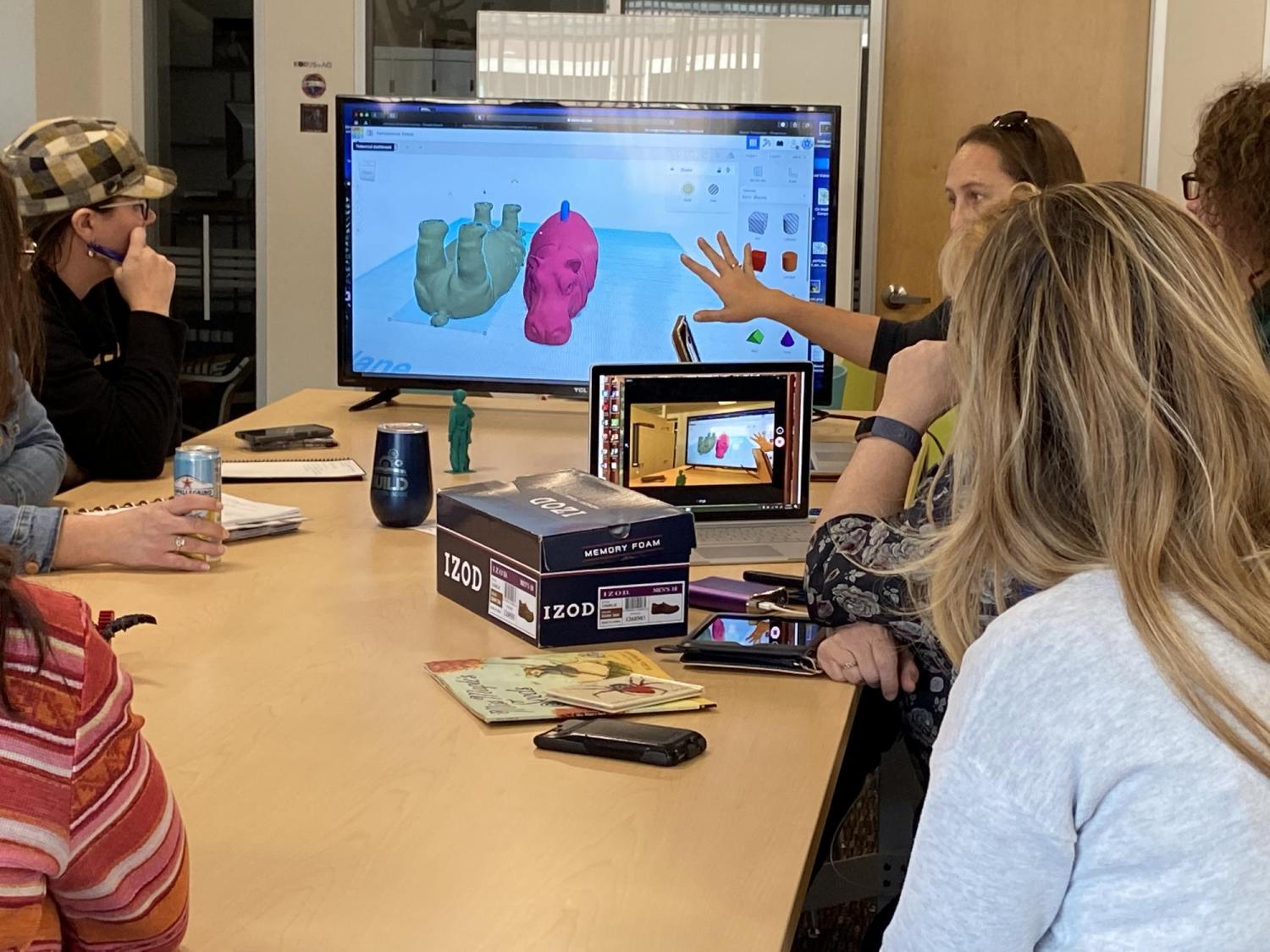 People sitting at a table watching a computer graphics demonstration