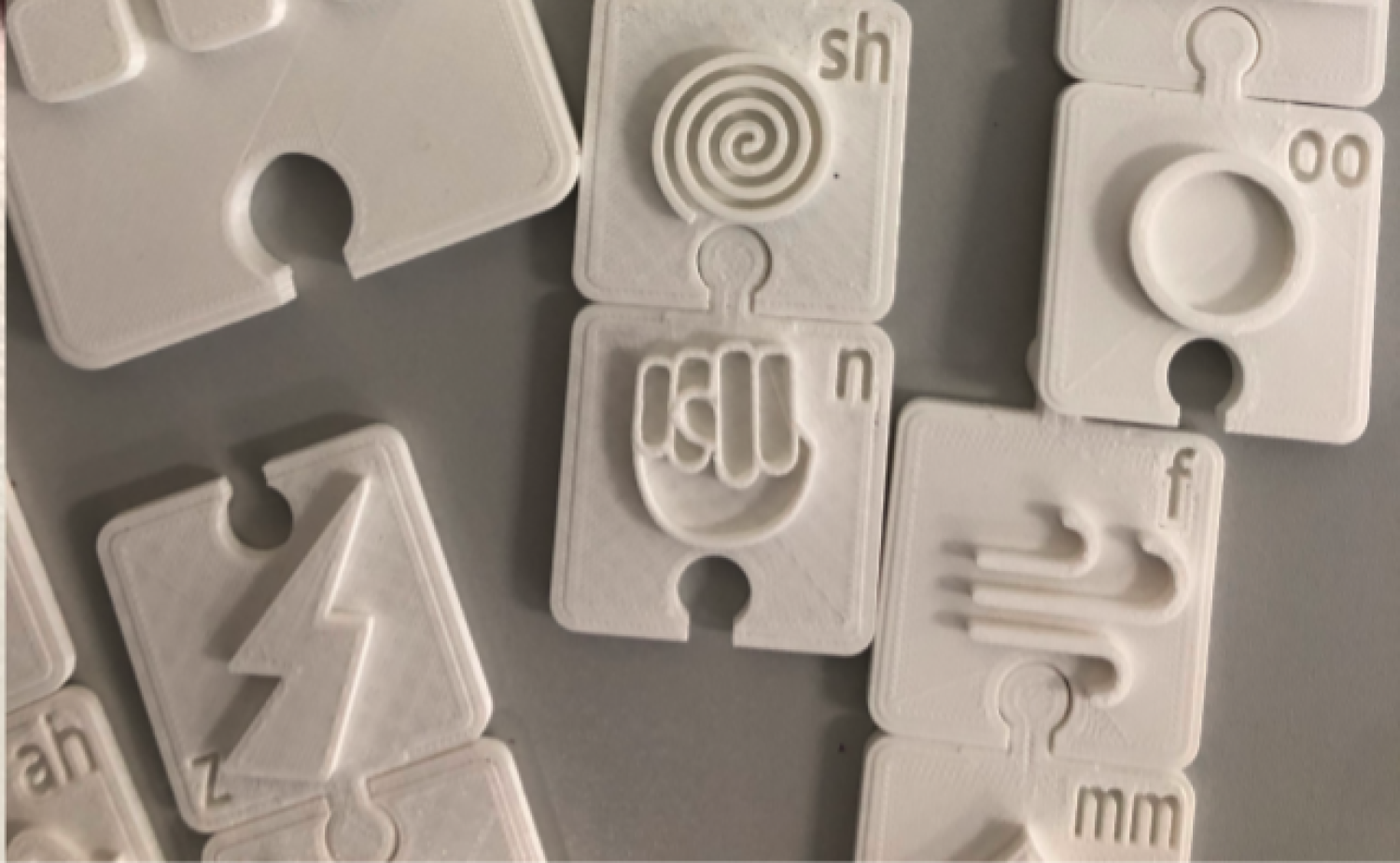 3D printed tactile puzzle pieces with raised icons and shapes.