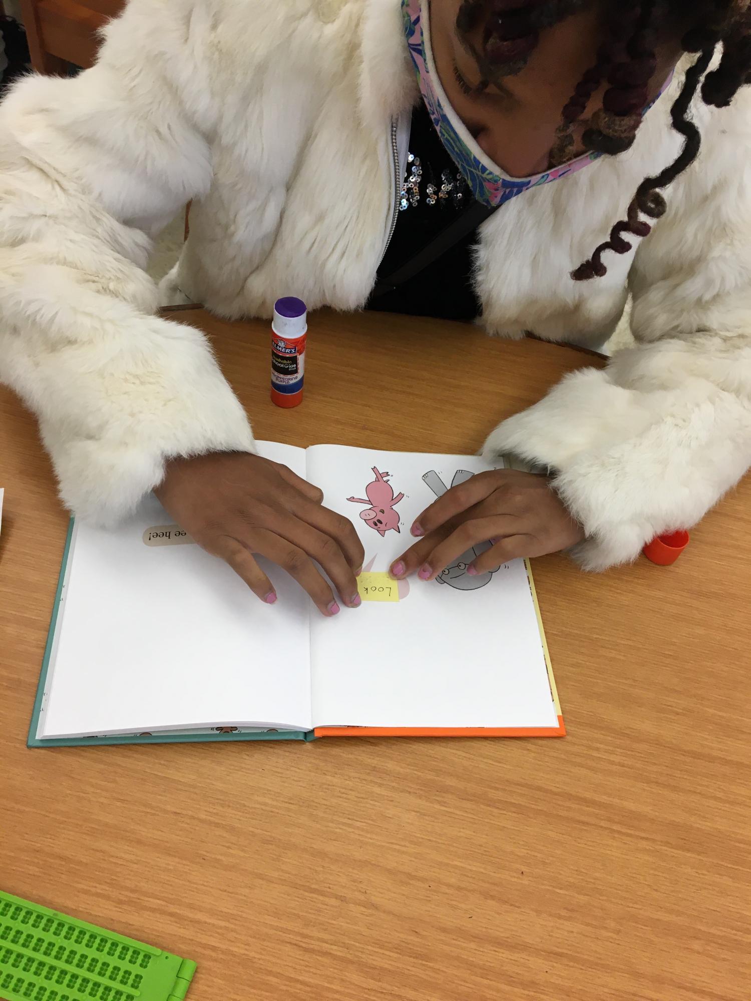 Girl adding braille to an Elephant and Piggie book.