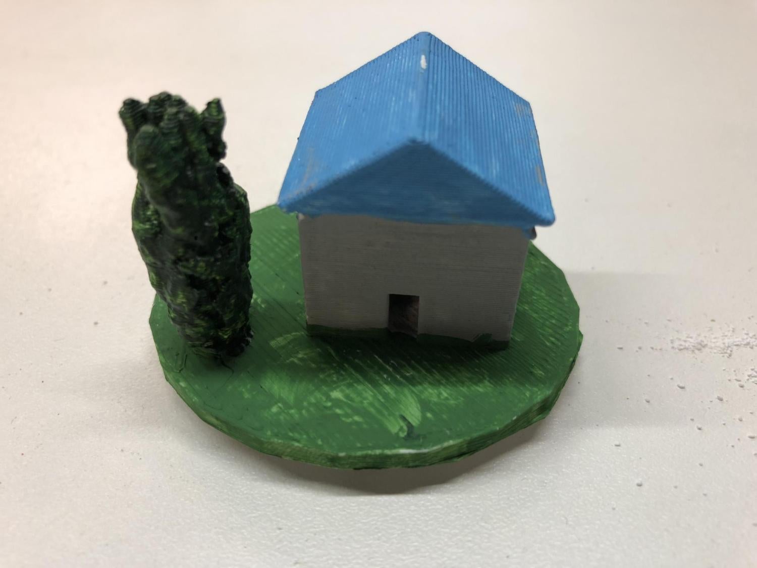 Playing piece with a small blue house and tree