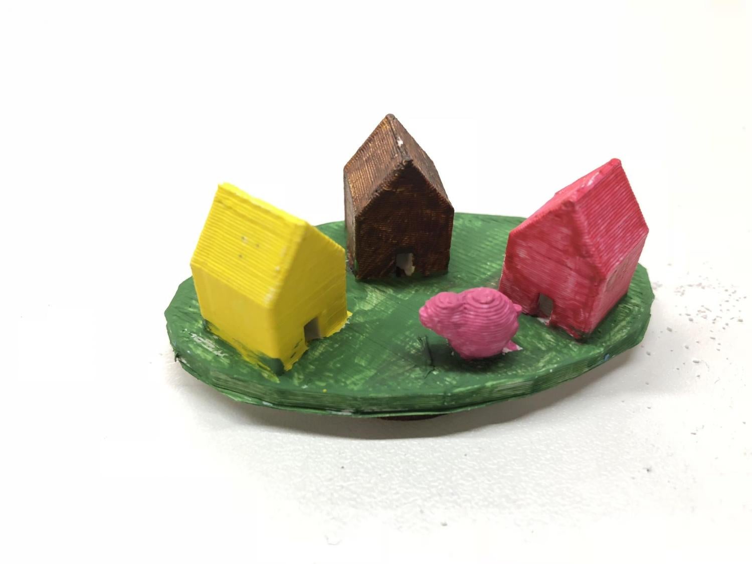 Playing piece with three small houses and a pink bush
