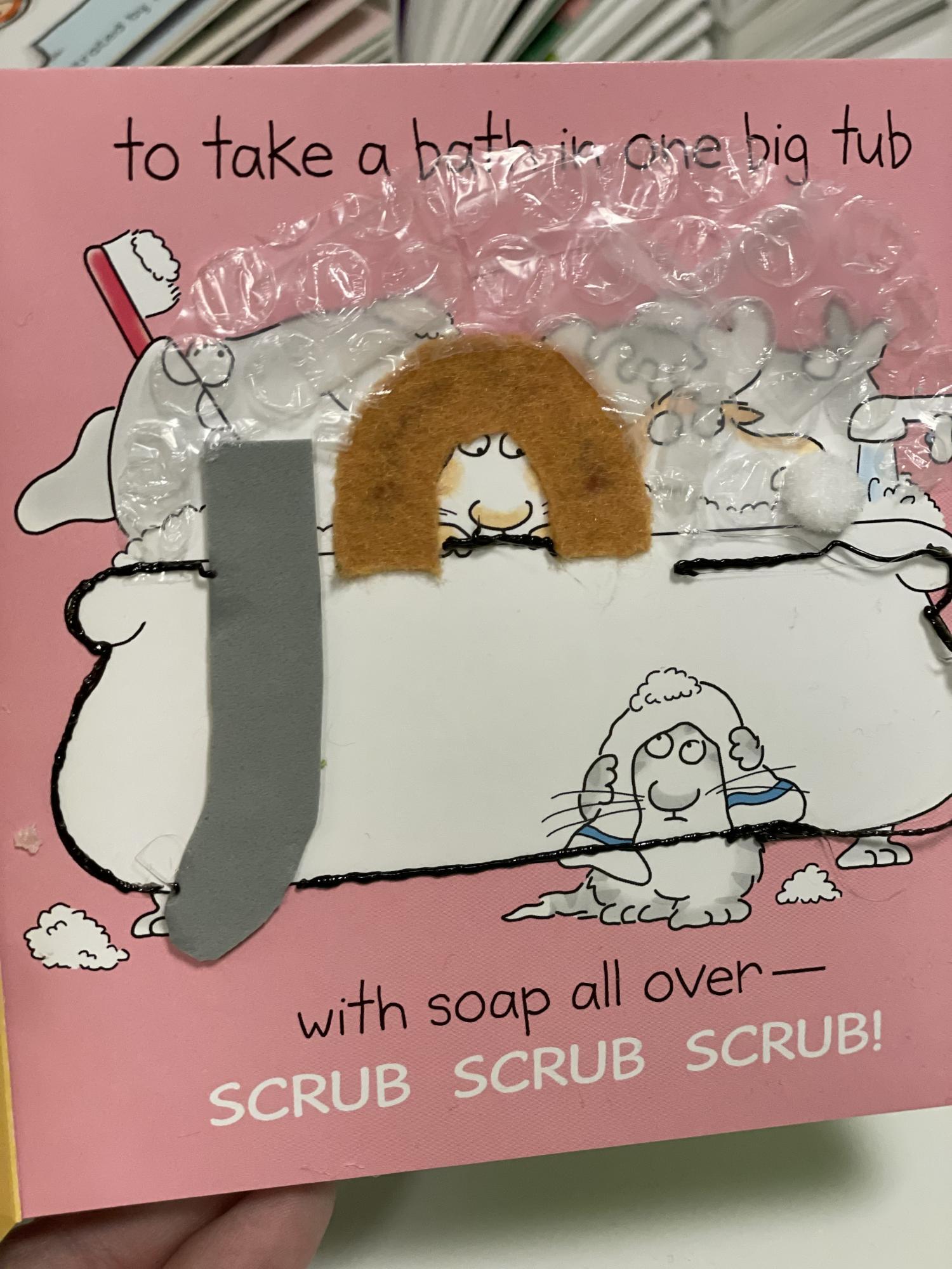 Tactile page with textures for an elephant, lion, and rabbit taking a bubble bath