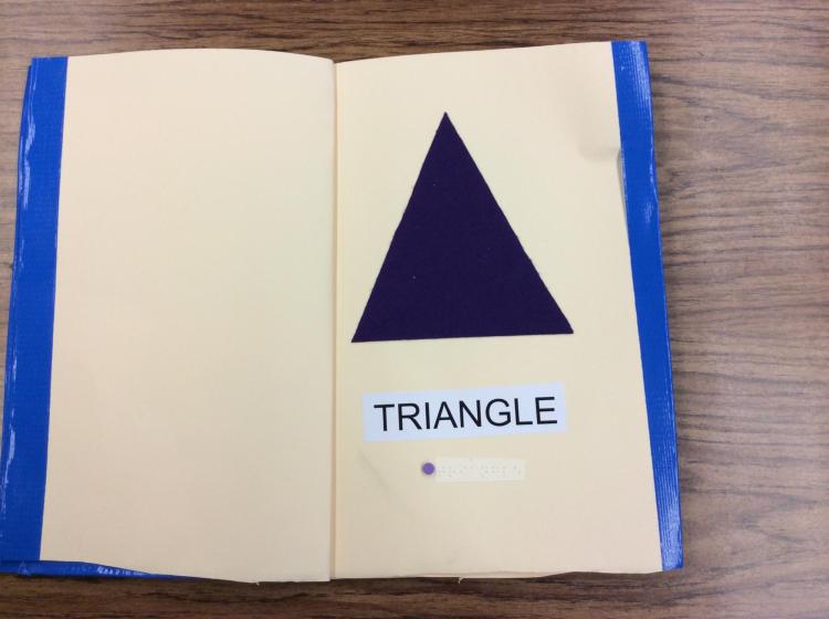 Page showing a large felt triangle with braille and English label.