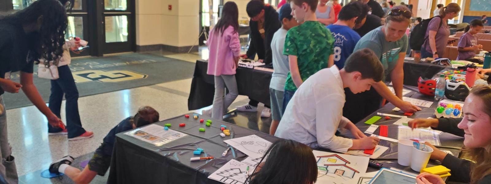 A group of people exploring tables at the CU NSF STEM Day Event