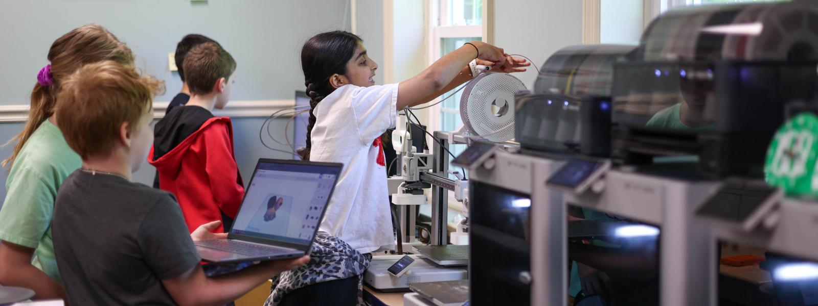 A group of kids using computers and 3D printers