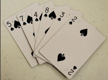Six playing cards showing different numbers in spades with braille.