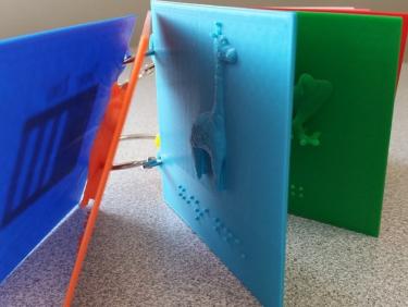 3D printed pages for Dear Zoo with braille and ring holes.