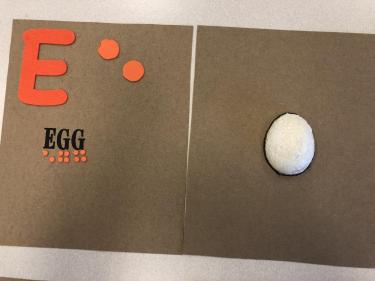 Book page for the letter E showing half of an egg made from white painted styrofoam.