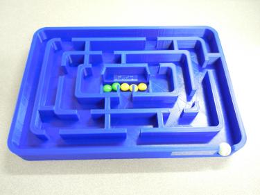 3D printed maze with raised walls and a marble for following the paths.