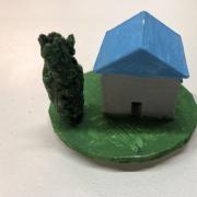 Playing piece with a small blue house and tree