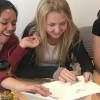 Three girls smiling and feeling tactile image on swell paper.