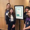 Three students and librarian posing with sign for Empathy Expo.