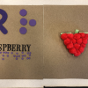 Tactile raspberry made from pom poms with word Raspberry in braille