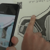 Hand pointing to parts of tactile map while using tactile images phone app