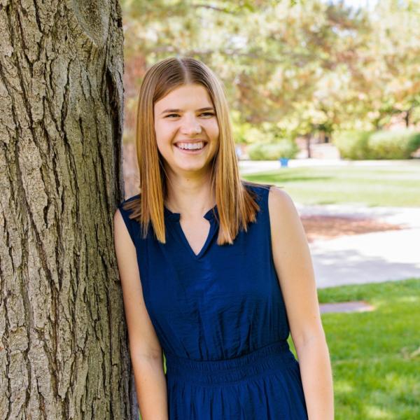 Woman standing by a tree smiling