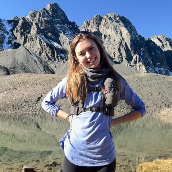 Woman smiling with hands on her hips in front of mountains
