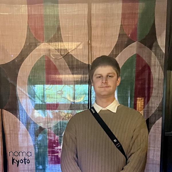 Man standing in front of tapestry
