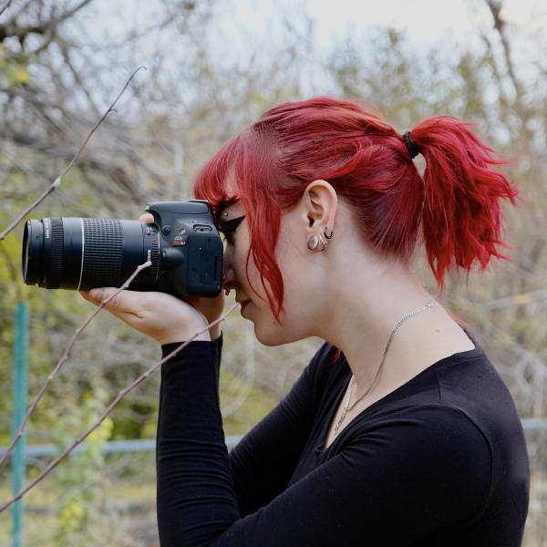 woman with red hair holding a DSLR