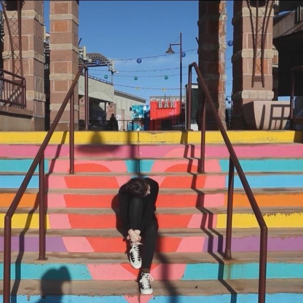 Person sitting on brightly colored steps with knee to head