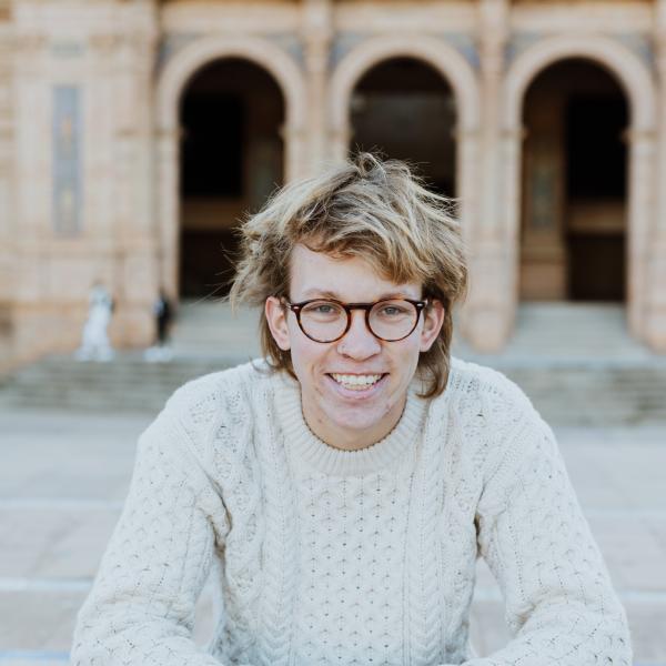 man with glasses sitting on a bench
