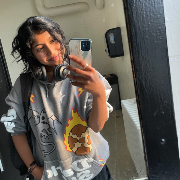 Anna Jacob - A person takes a selfie in a mirror with headphones around their neck