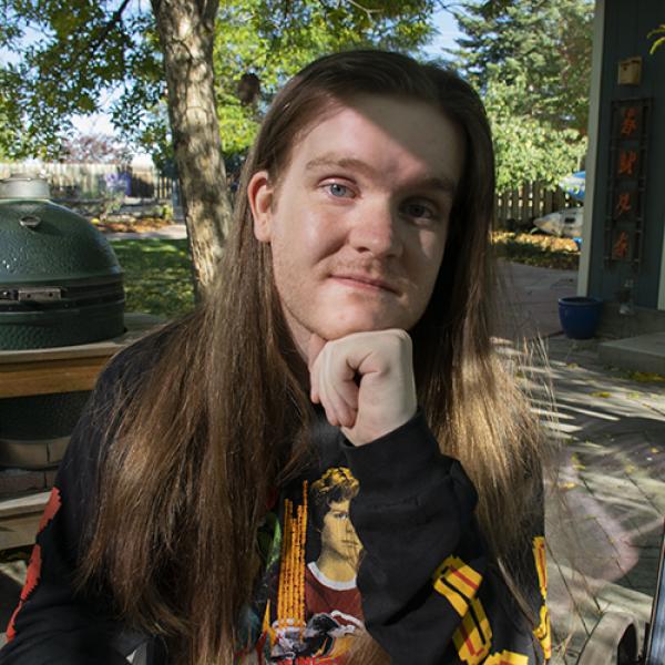Person sitting outdoors with chin resting on fist