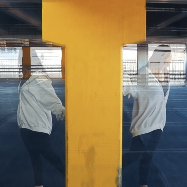 Mirrored image of person in a carpark beside a yellow structure