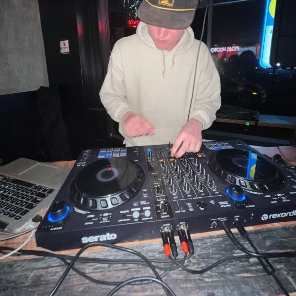 Jack Hogan - A person DJing at an event, focused on adjusting controls on a DJ mixer.