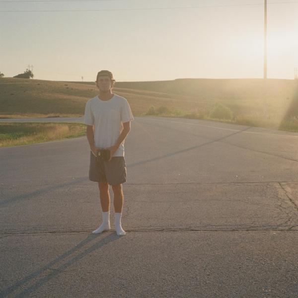 man standing on a road with sun behind him