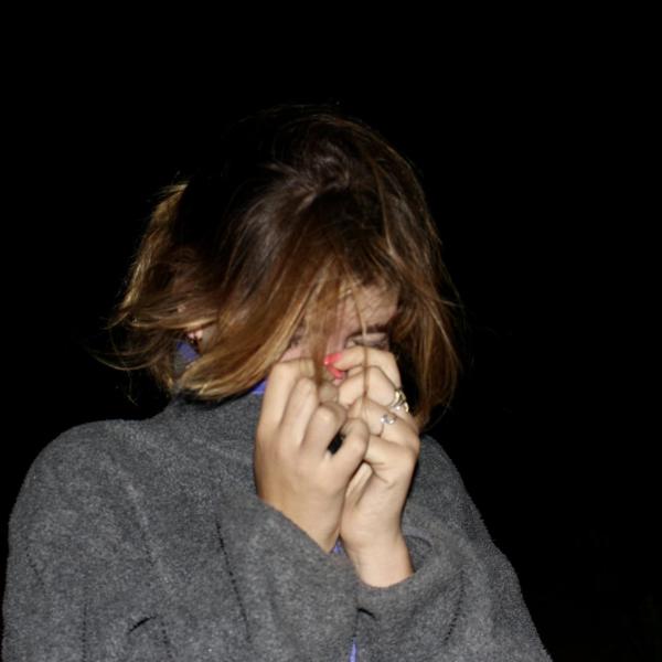 woman covering her face with her hands in front of black background
