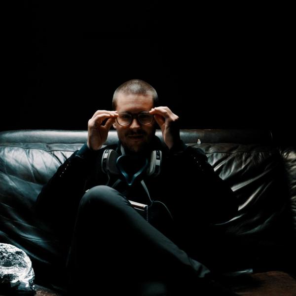 man sitting on a black sofa in a darkened room