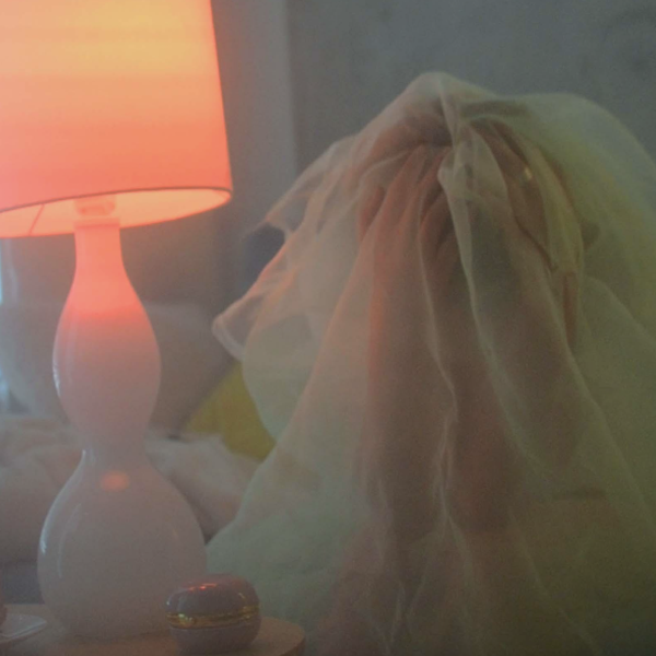 Person wearing bridal headress sitting by a lamp