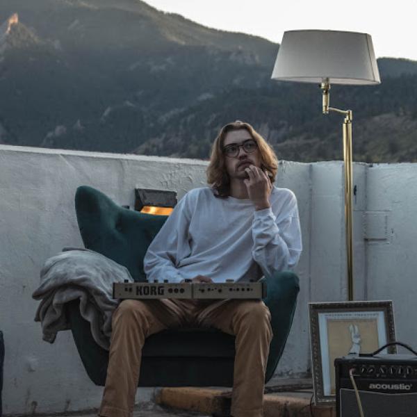 man sitting in a chair with mountains behind him