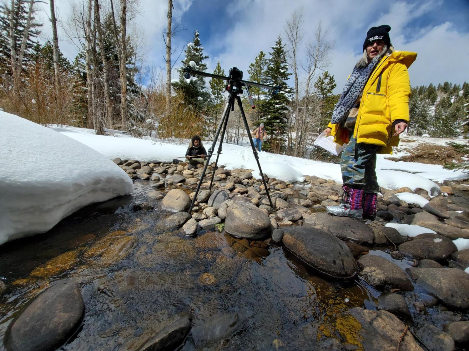 Behind the scenes camera-person standing in a creek with camera