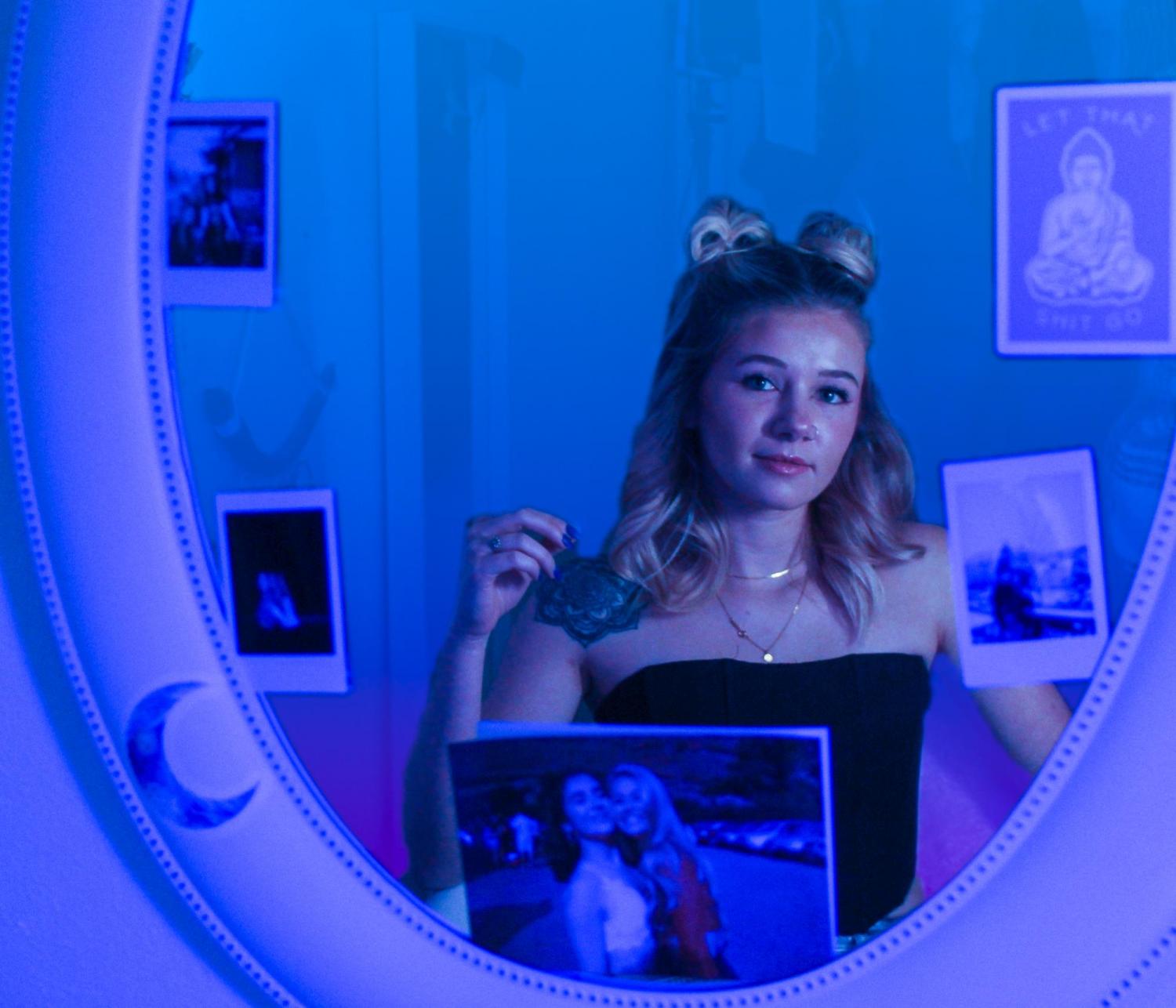 Woman in a blue room, looking into mirror and smiling