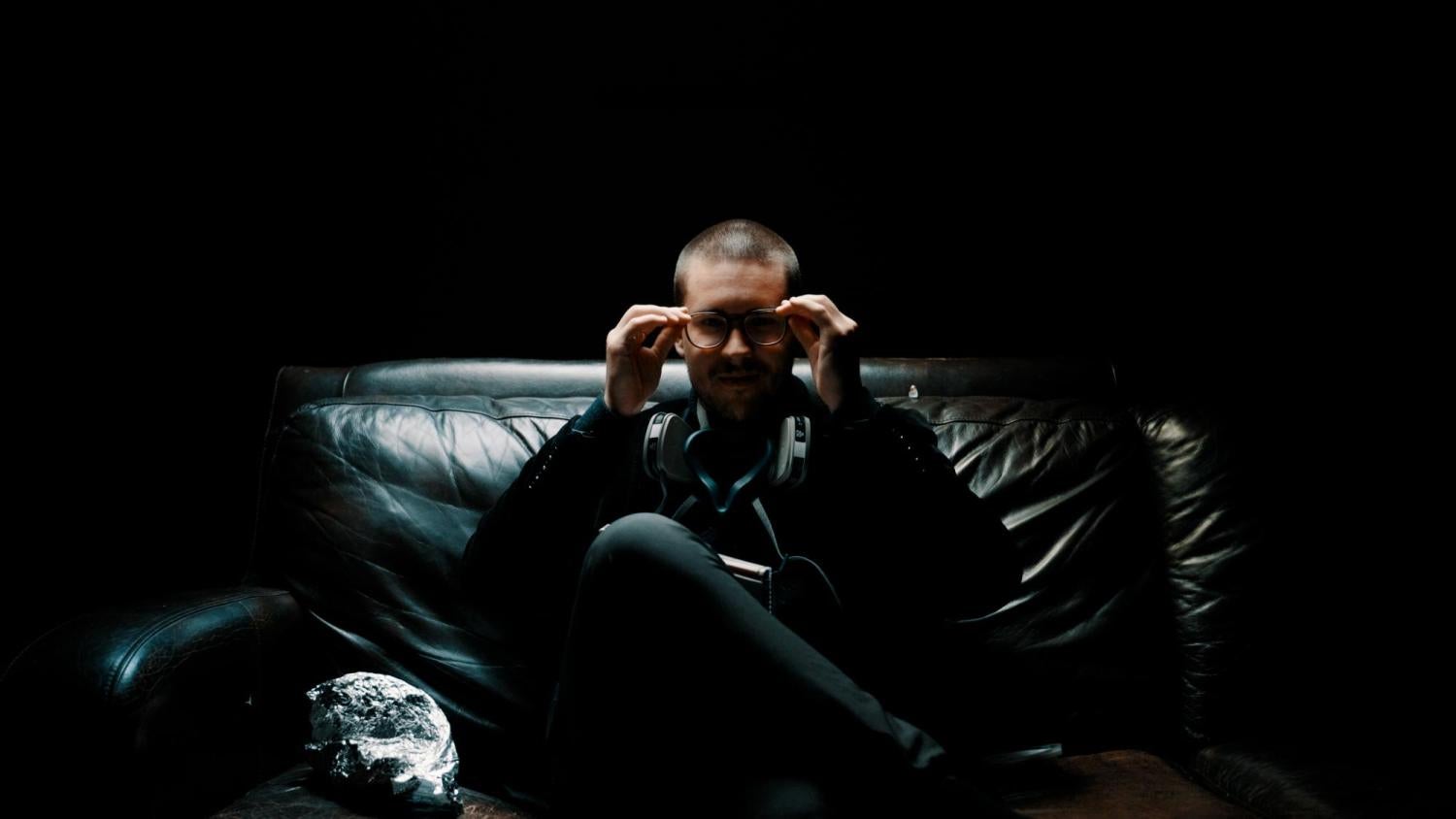 man sitting on a black sofa in a darkened room