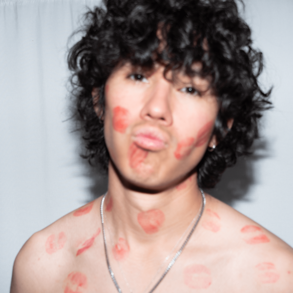 Esai Vargas - A close-up of a person with curly hair and lips covered in kiss marks, making a playful expression.