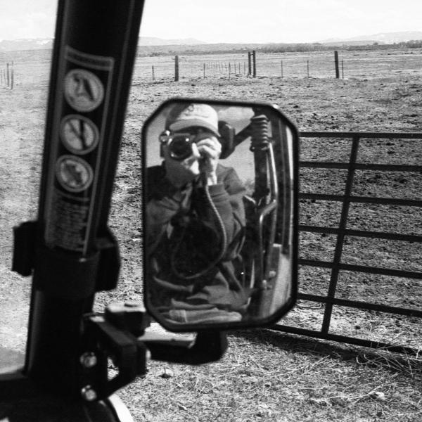Jake Daxner - A person takes a photo of their reflection in a side mirror of a vehicle.
