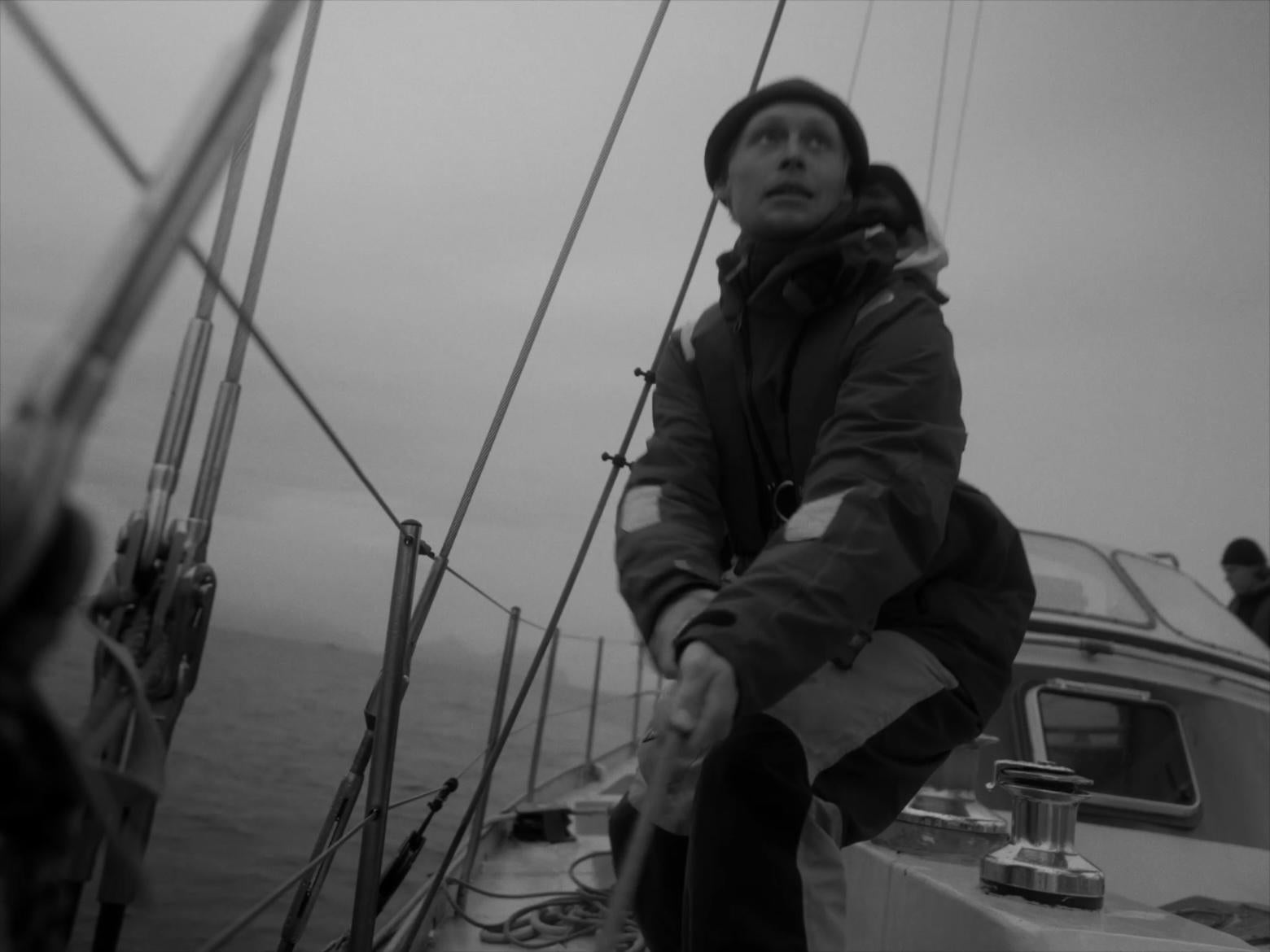B&W sailor pulling rope tight on boat